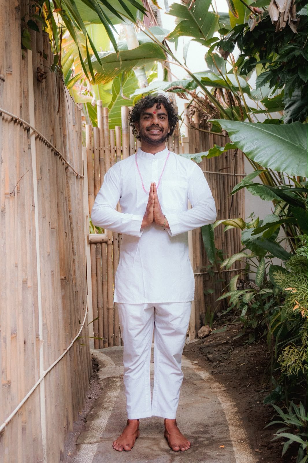 Navin standing in a peaceful garden with namaste gesture